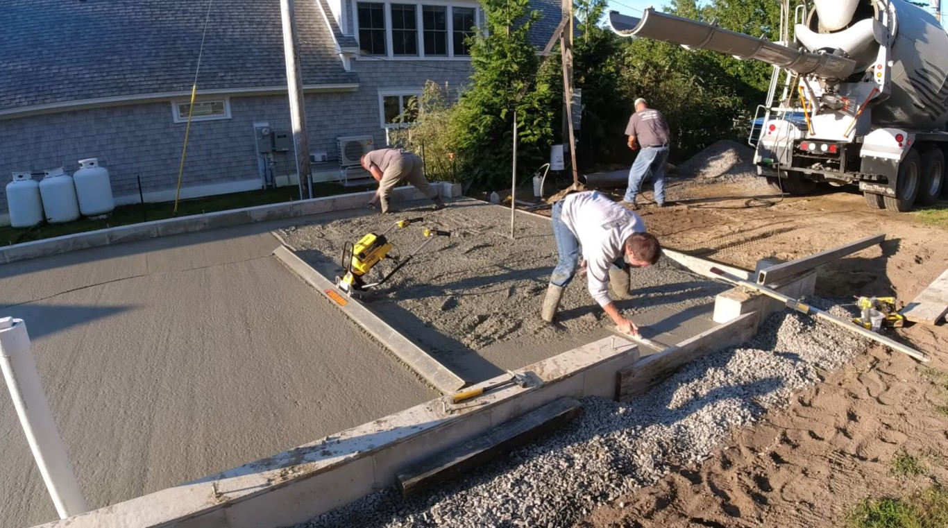 Expert concrete team performing precision grading and base preparation